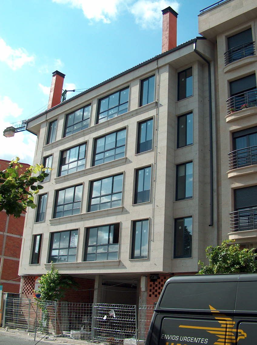 Un edificio con muchas ventanas y una camioneta estacionada frente a él.