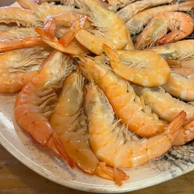 Un plato de camarones está sobre una mesa de madera.