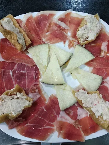 Un plato blanco cubierto con carne y queso sobre una mesa.