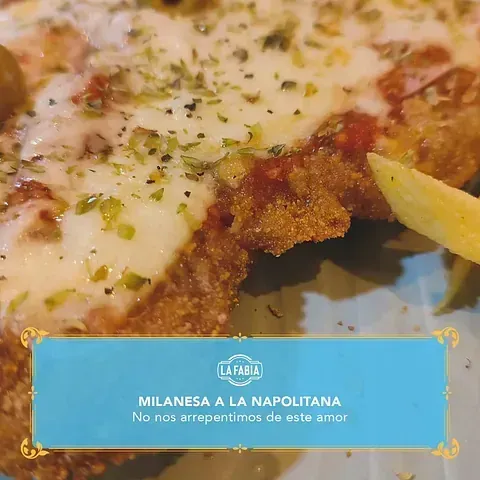 Primer plano de una milanesa a la napolitana con queso y hierbas. El texto debajo dice 