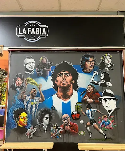 Mural de Diego Maradona rodeado de otras figuras argentinas, frente al logo de