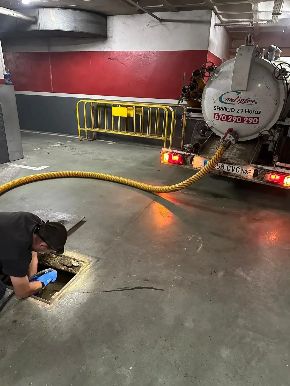 Un trabajador con guantes inspecciona un desagüe