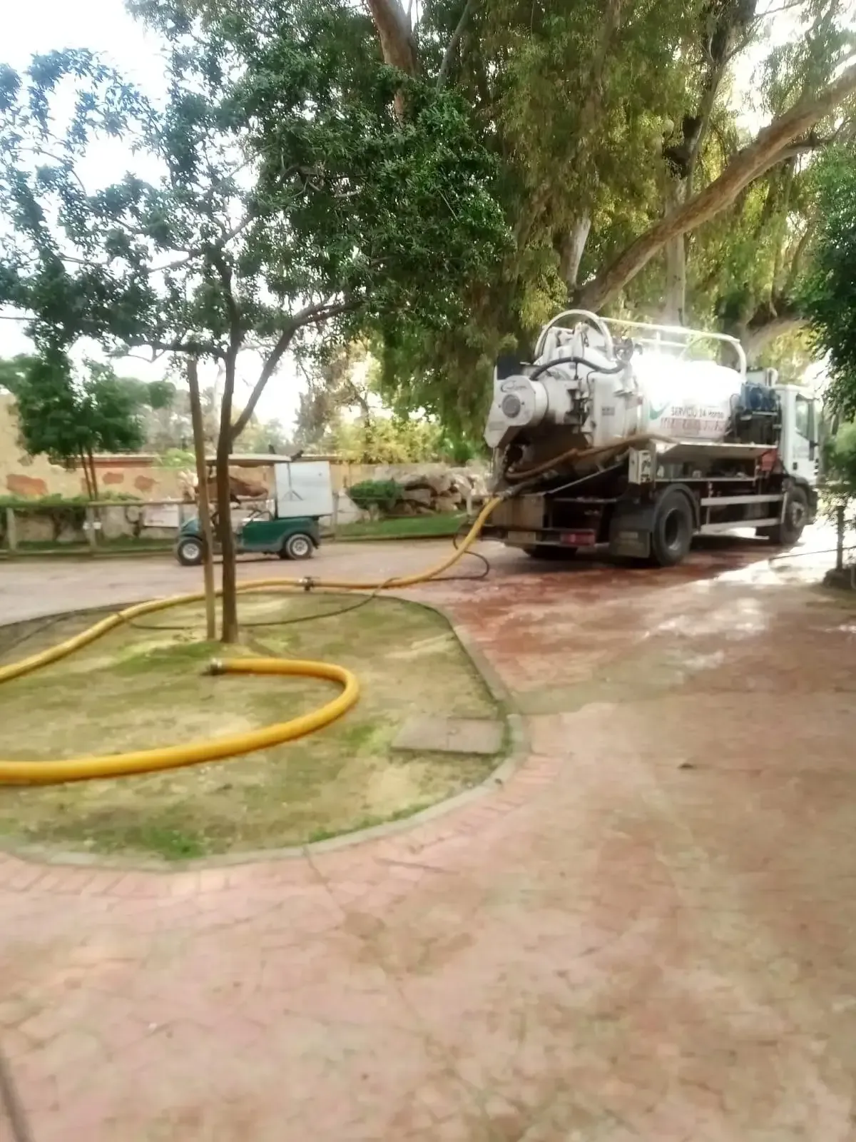 Un camión aspirador estacionado en un patio utiliza una manguera amarilla para extraer líquido de una fuente subterránea.