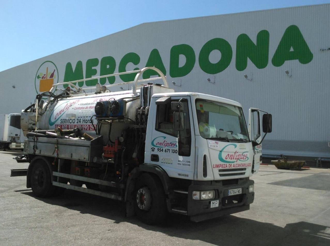 Camión cisterna de combustible estacionado frente a un almacén de Mercadona.