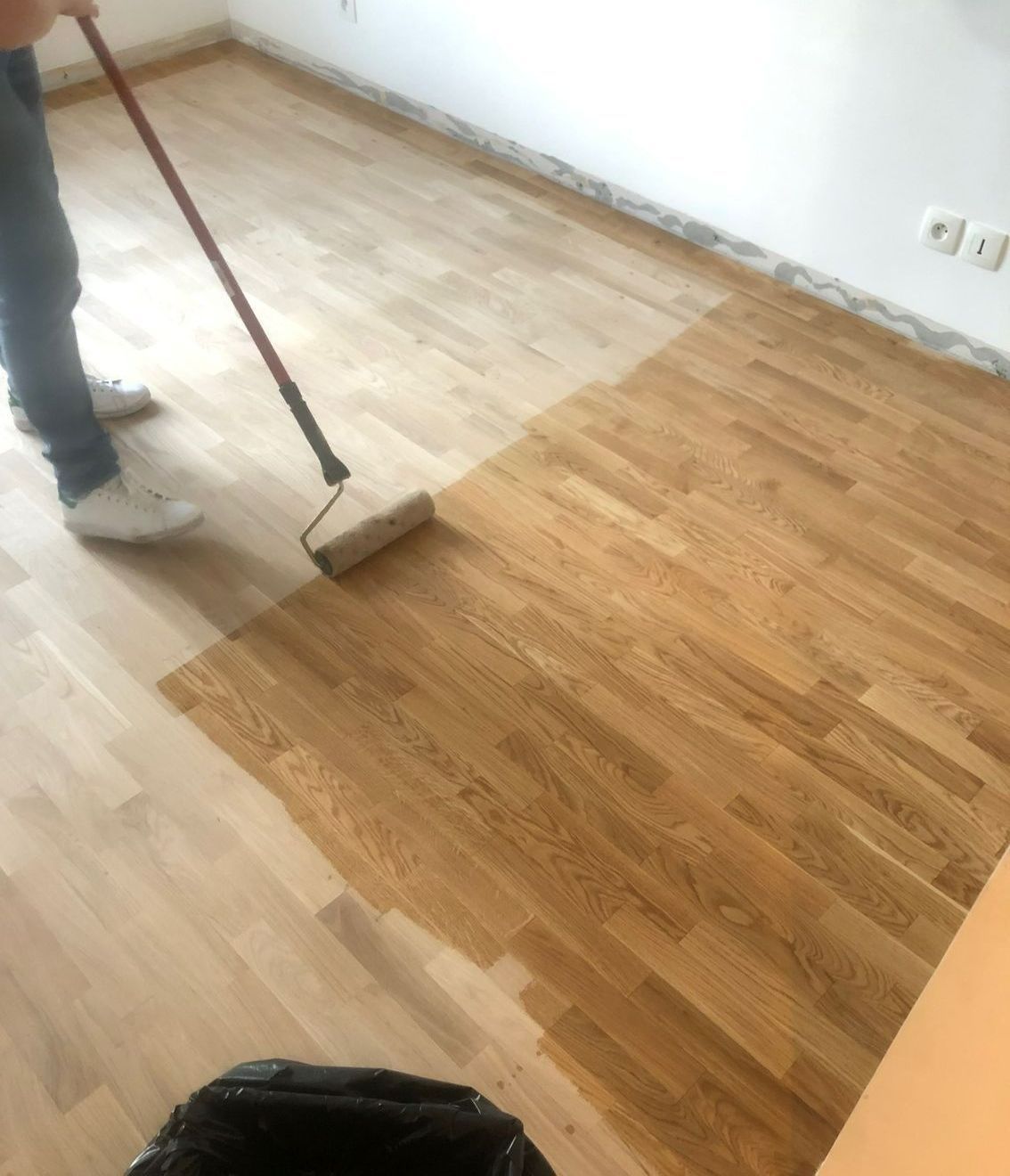 Une personne passant un rouleau sur un parquet