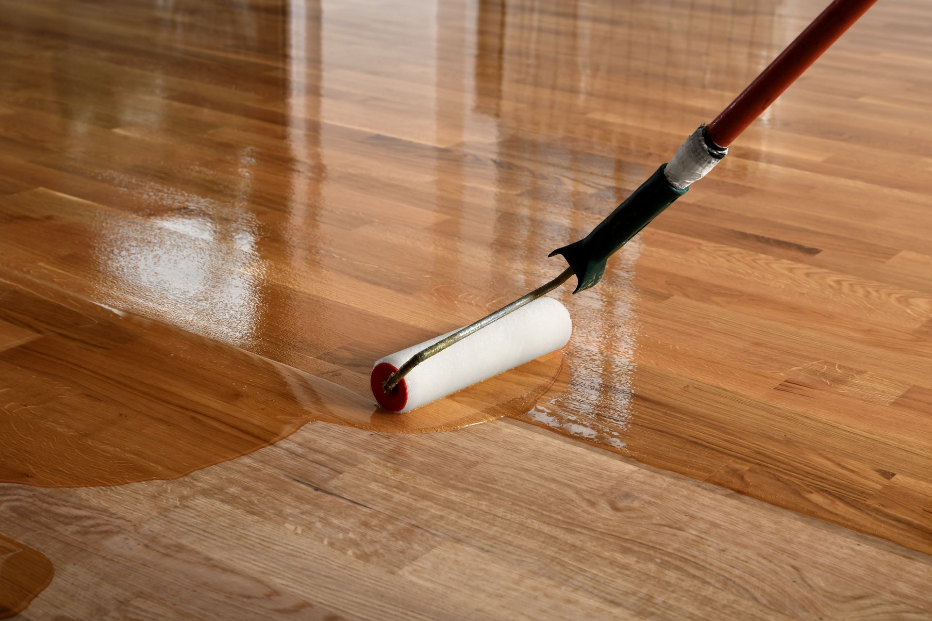 Un rouleau appliquant du vernis sur un parquet