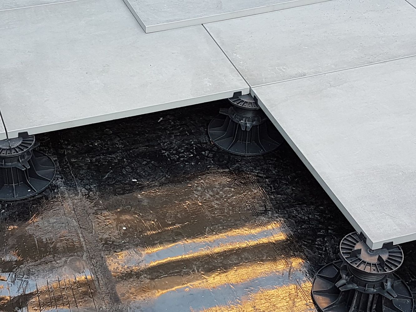 Carrelage blanc surélevé sur supports circulaires au-dessus d'une surface sombre et humide aux reflets jaunes