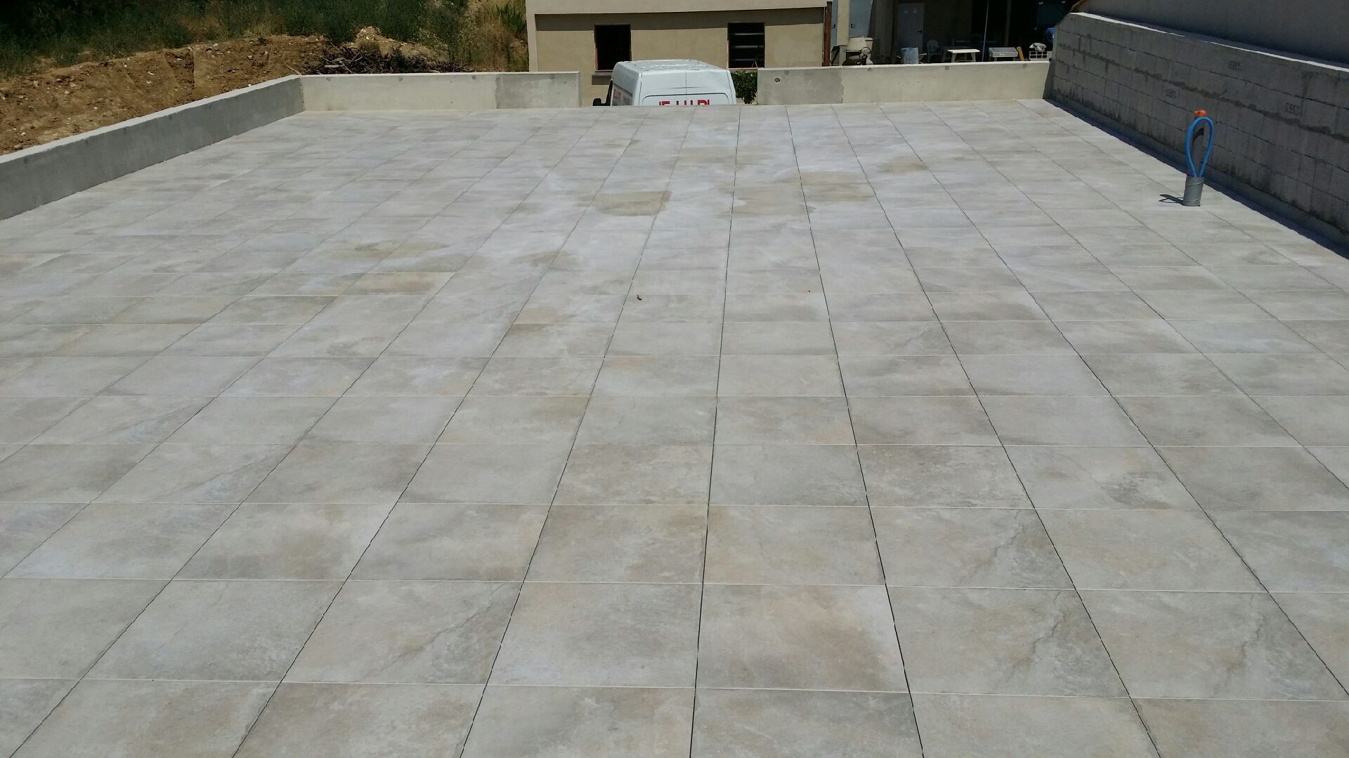 Terrasse carrelée vide sur le toit, murets bas et collines au loin en arrière-plan