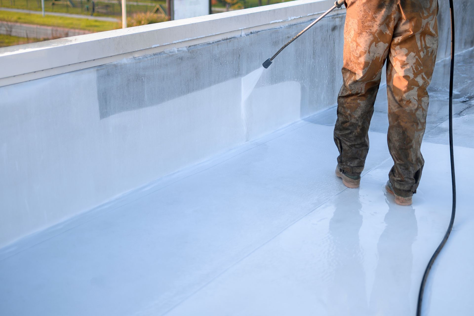 Ouvrier appliquant un revêtement blanc imperméable à l'intérieur d'une piscine ou d'un réservoir en béton