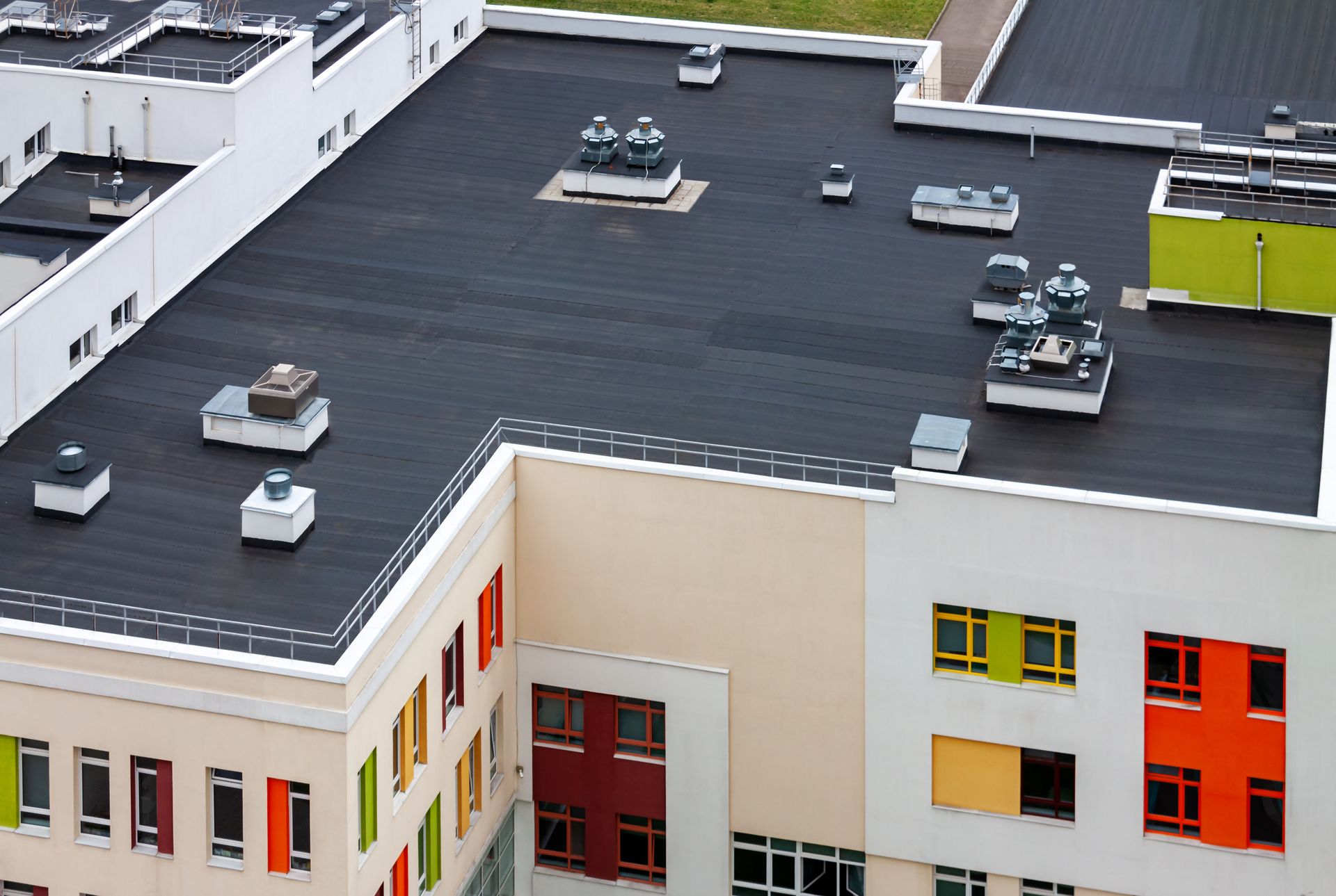 Vue aérienne du toit d'un immeuble avec des unités de climatisation et des fenêtres d'appartements colorées