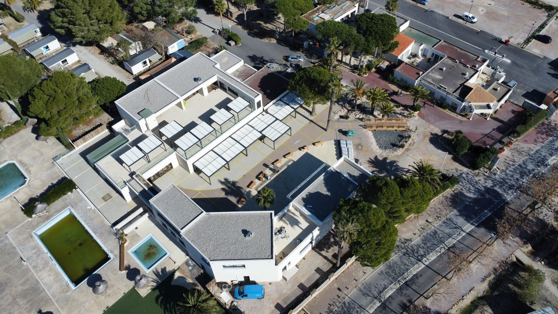 Vue aérienne d'un grand bâtiment avec une cour intérieure, une piscine et des arbres et rues environnantes