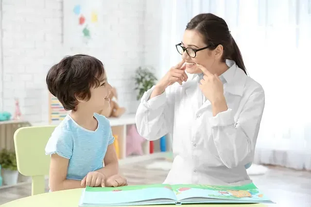 Una mujer está hablando con un niño pequeño que está sentado en una mesa.