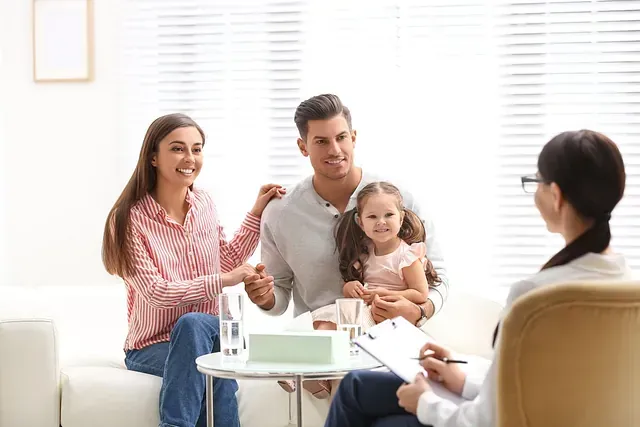 Una familia está sentada en un sofá hablando con una psicóloga.