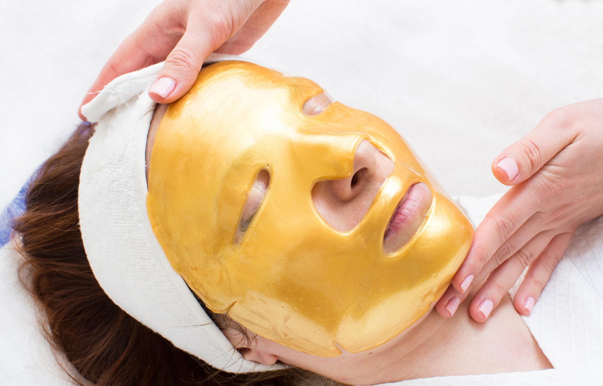 Una mujer se pone una máscara de oro en la cara.