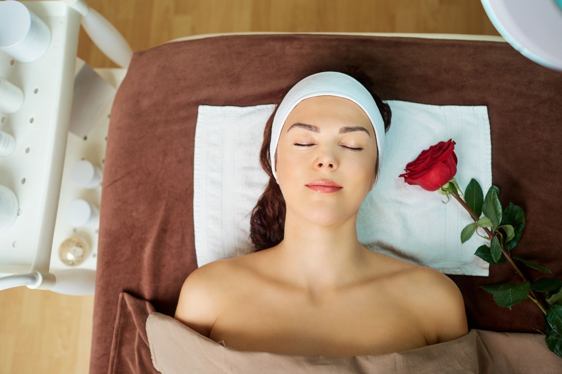 Una mujer está acostada en una cama con los ojos cerrados y una rosa en la cara.