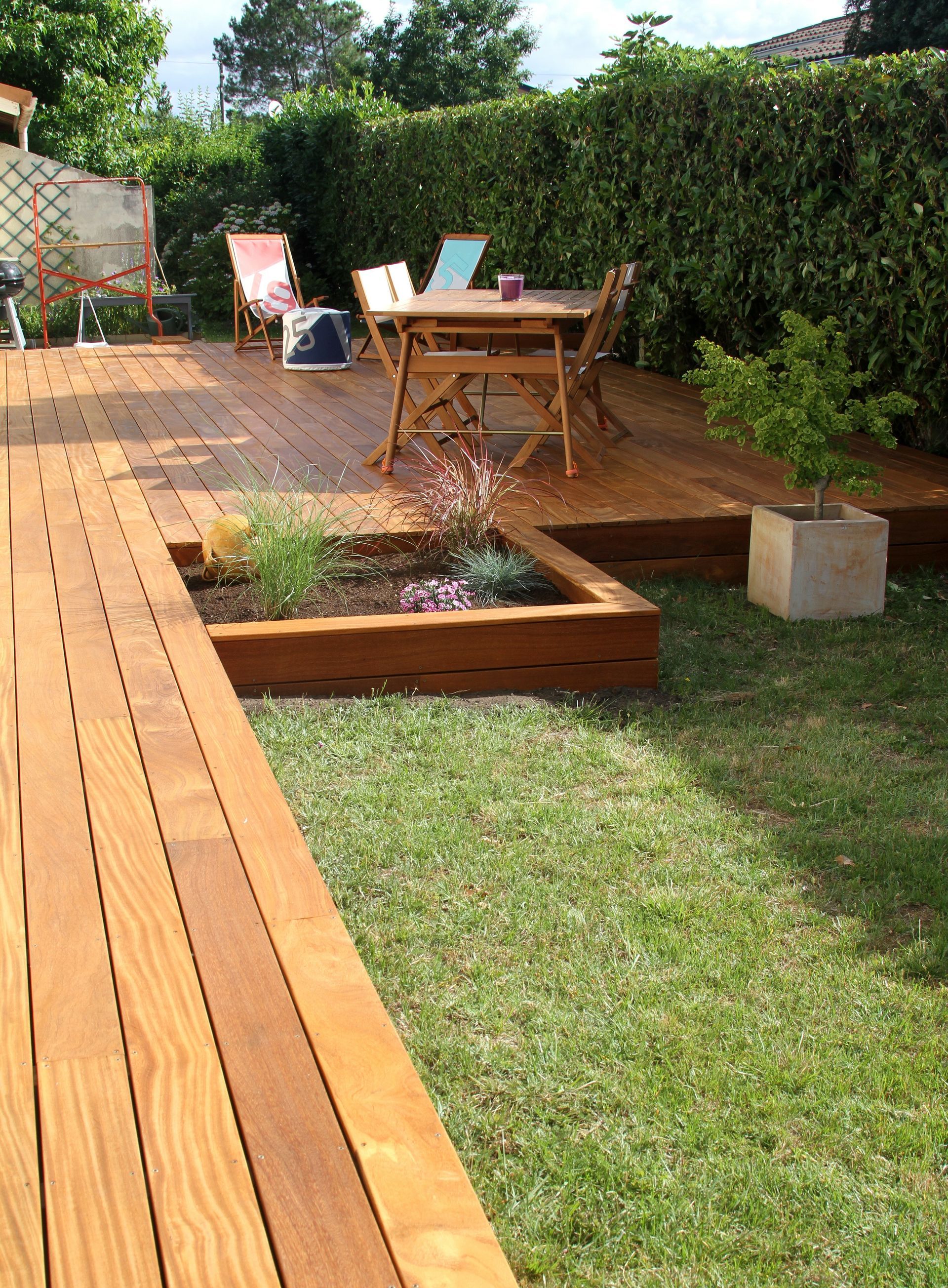 Une terrasse en bois avec un parterre de fleurs.
