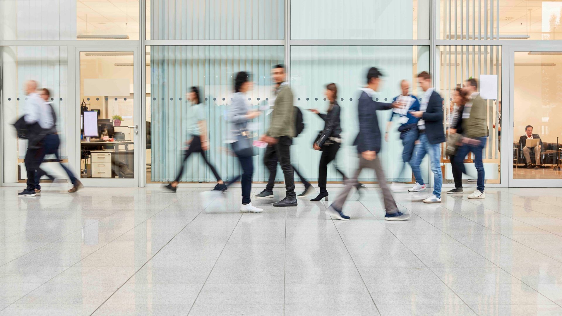 Menschen verschwammen vor dem inneren Auge, als sie in einem modernen Gebäude mit Glaswänden entlanggingen.