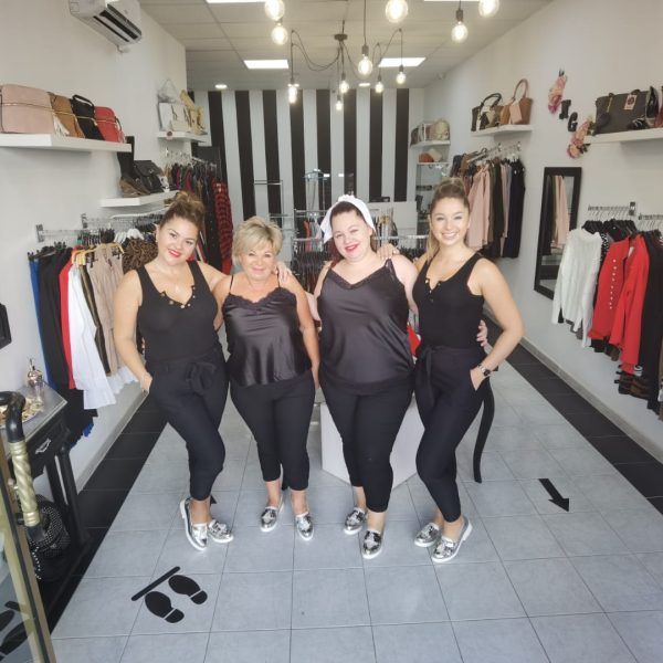 Cuatro mujeres posan para una foto en una tienda de ropa.