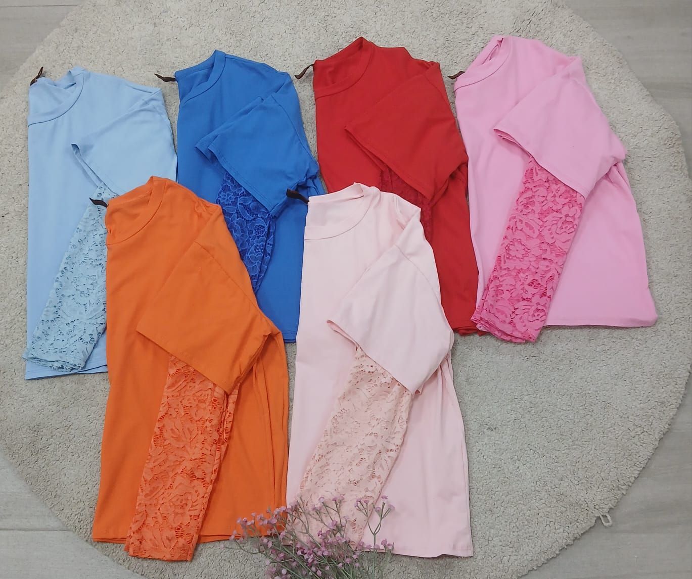 Un montón de camisas de diferentes colores están sobre una alfombra.