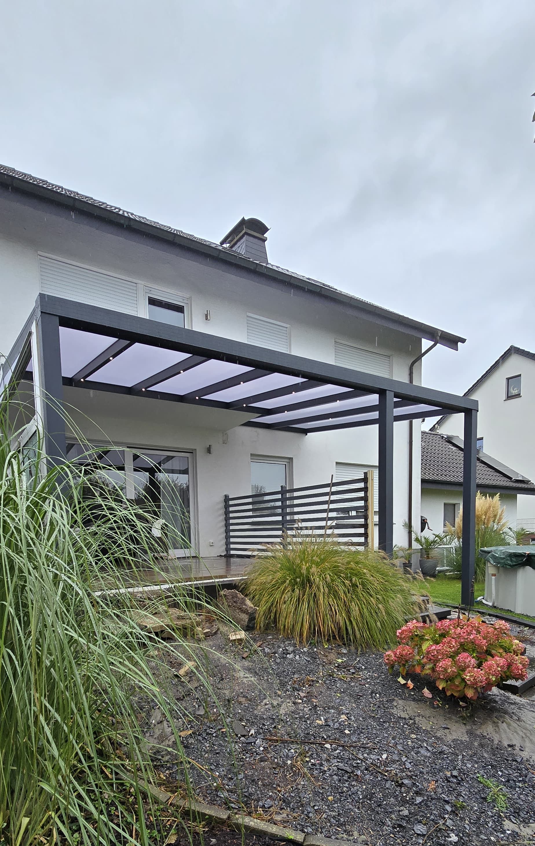 Ein weißes Haus mit einer Pergola im Hinterhof.