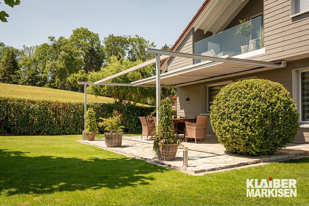 Ein Haus mit einer Terrasse und einer Pergola im Hinterhof.