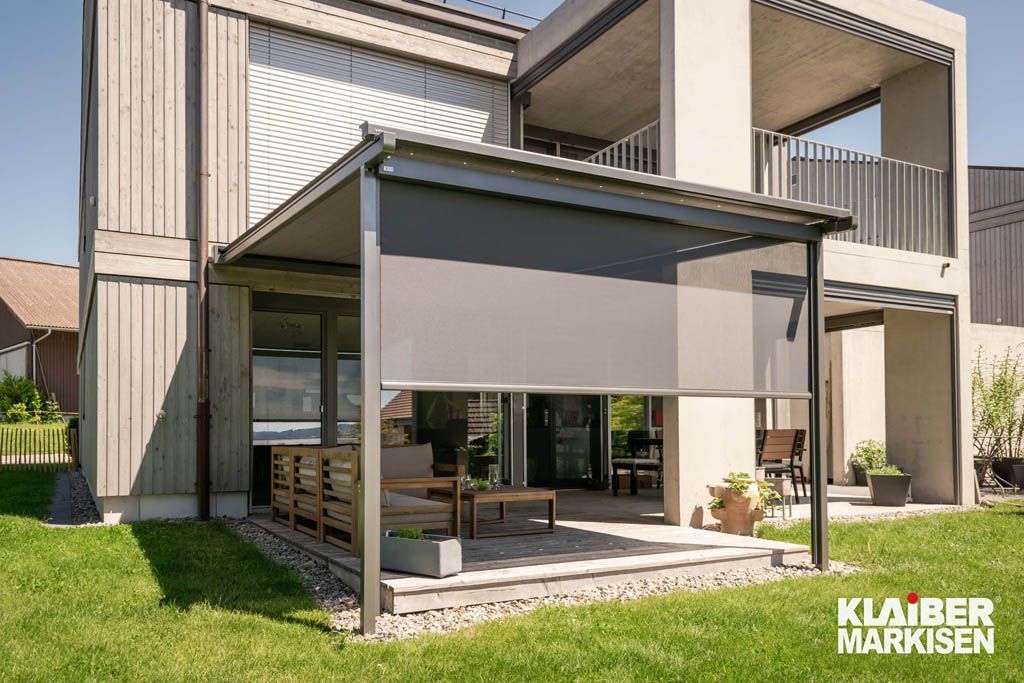 Ein Haus mit Pergola und davor liegender Terrasse.