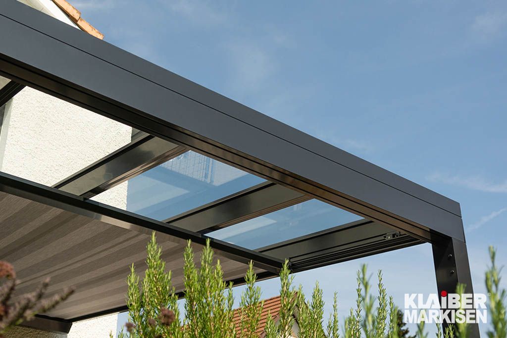 Vor einem Haus steht eine Pergola mit Glasdach.