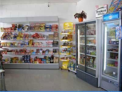 Pasillo de una tienda de conveniencia con aperitivos, bebidas y una vitrina refrigerada
