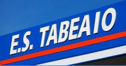 Cartel azul con el texto blanco «E.S. TABEAIO» y una franja roja diagonal debajo