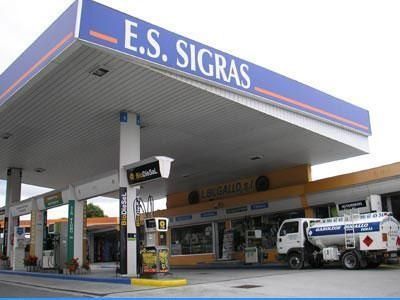 Marquesina de gasolinera con letrero de E.S. SIGRAS, surtidores y un vehículo de servicio aparcado en el exterior