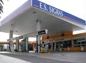 Marquesina de gasolinera con el letrero «E.S. SIGRAS» y surtidores en una estación de carretera