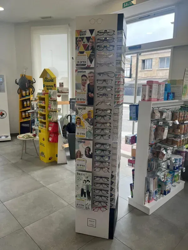 Interior luminoso de la farmacia, con estanterías de productos y tarjetas de felicitación cerca de grandes ventanales.