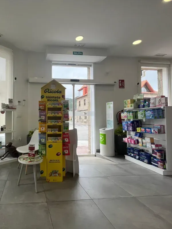 Interior de una pequeña tienda con estantes para aperitivos, un expositor amarillo y una puerta principal abierta a la calle.