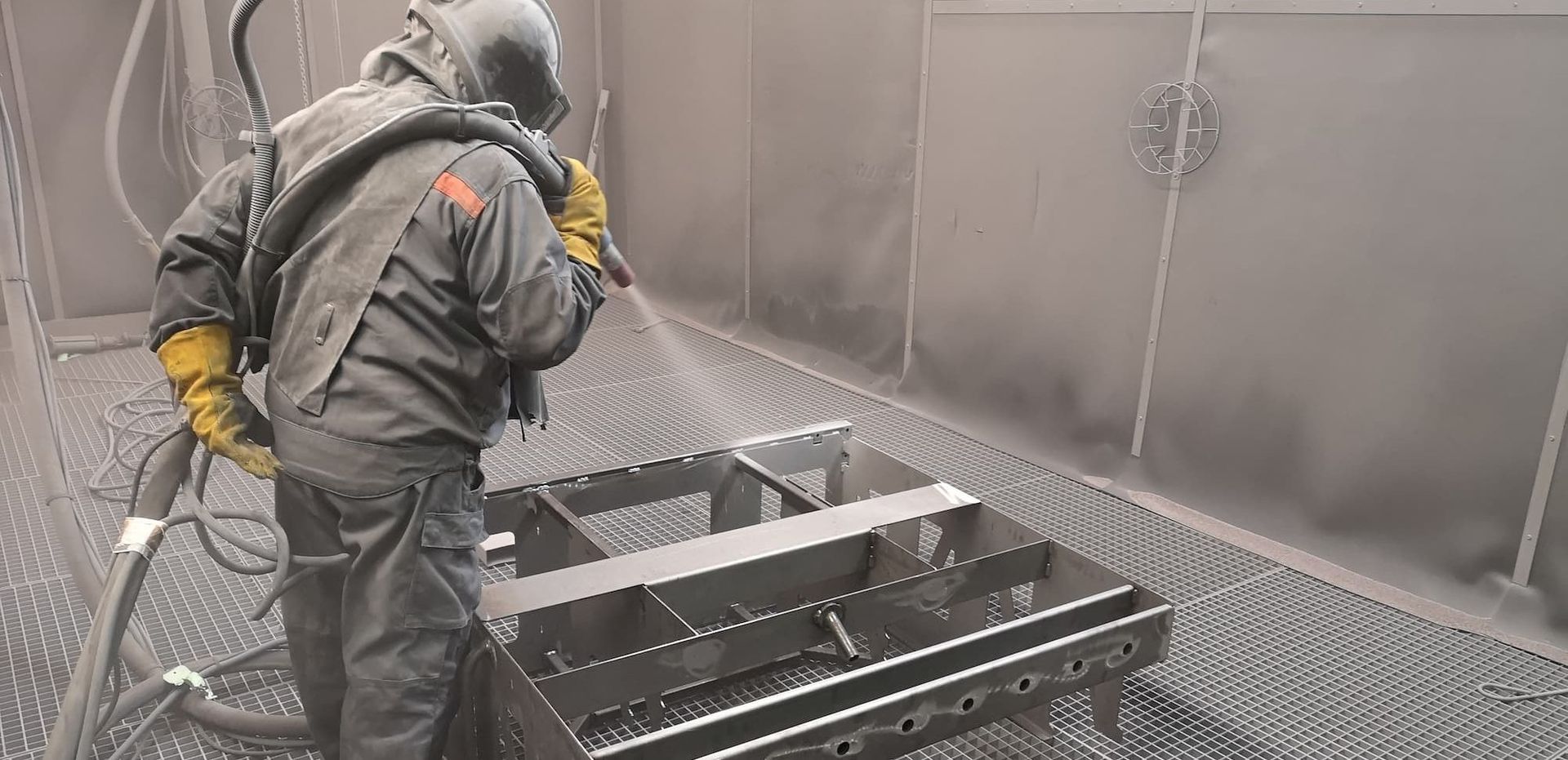 Opérateur grenaillant une structure métallique en cabine chez GAP Industrie