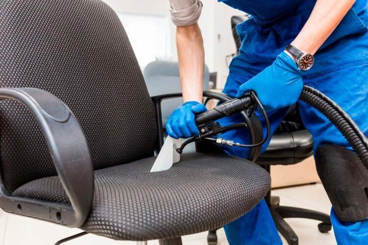 Uma pessoa está limpando um assento de carro azul com um aspirador de pó.