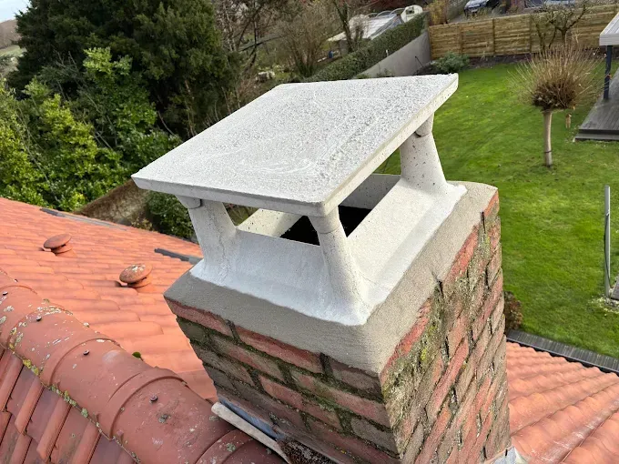 Une cheminée est posée sur un toit de tuiles rouges.