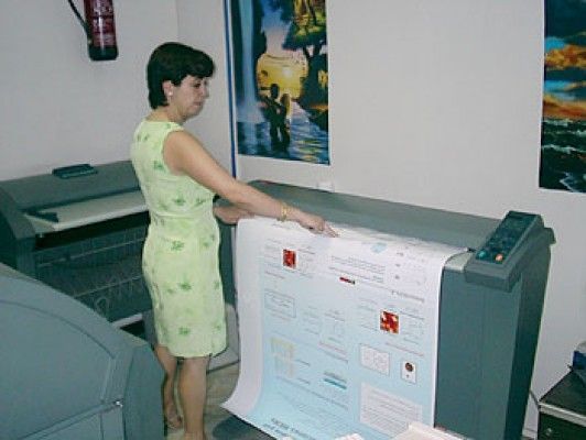 Mujer ajustando la salida de una impresora de gran formato en la oficina.