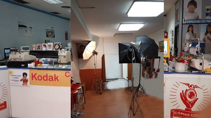Interior de un estudio fotográfico con mostrador y cartel de Kodak a la izquierda, equipo de iluminación en el medio y pantalla a la derecha.