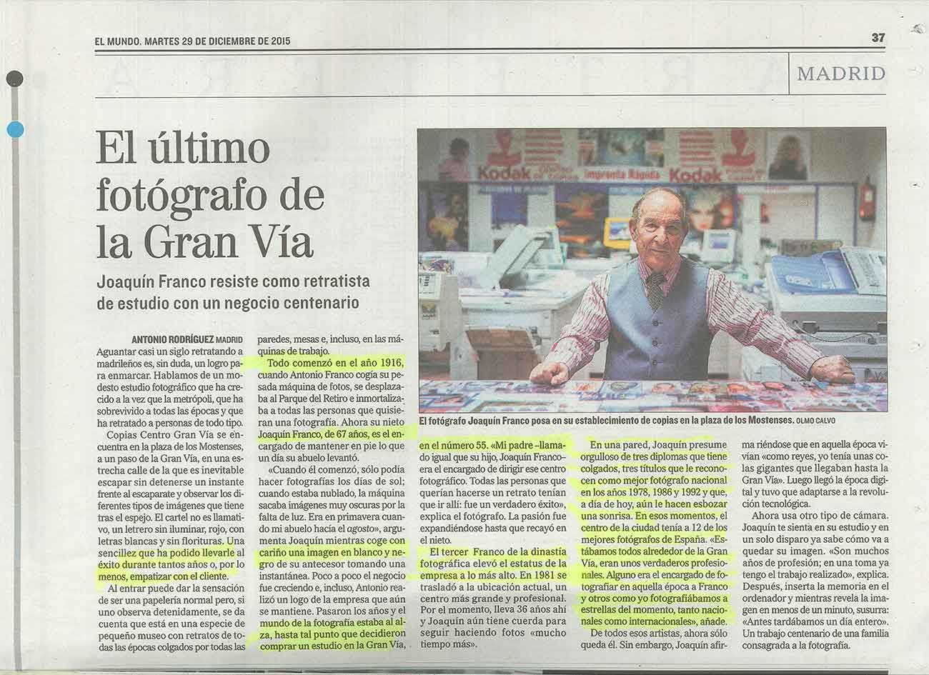 Artículo de periódico sobre un fotógrafo en la Gran Vía. Un hombre está sentado en su tienda, rodeado de fotografías.