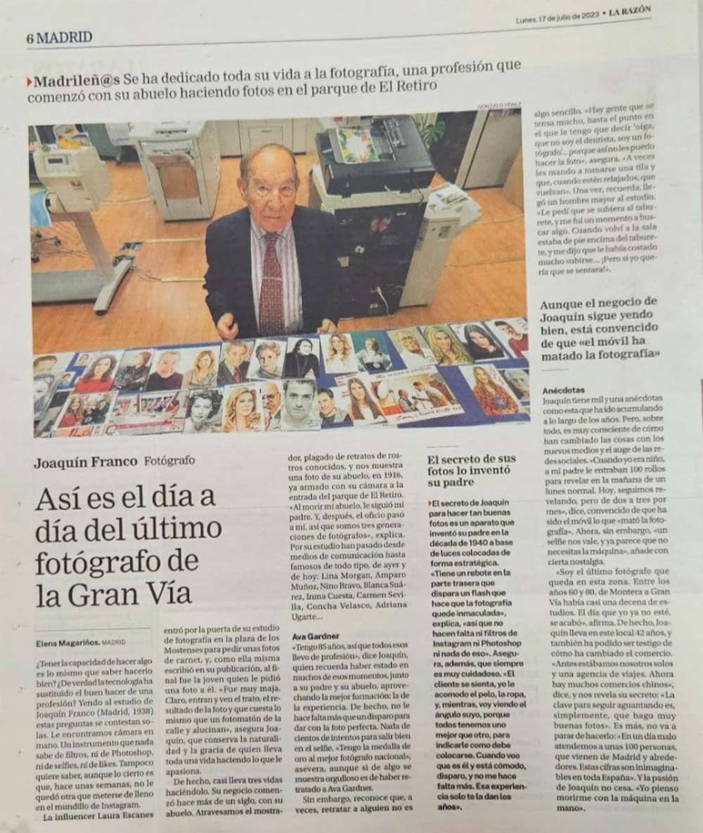 Hombre de traje junto a una fotocopiadora, rodeado de fotos sobre una mesa. Artículo de periódico sobre un fotógrafo.