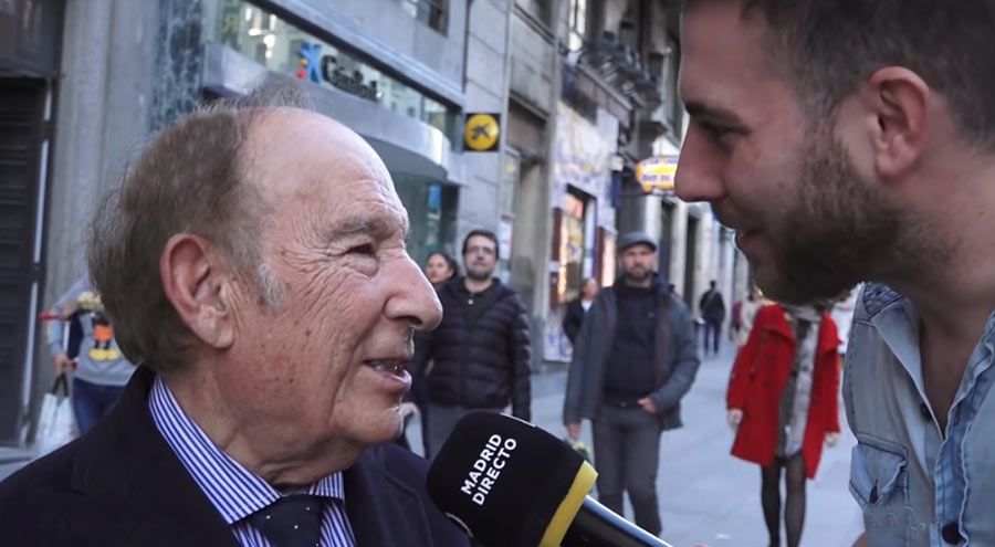 Hombre siendo entrevistado en una calle de la ciudad; micrófono, entrevistador.