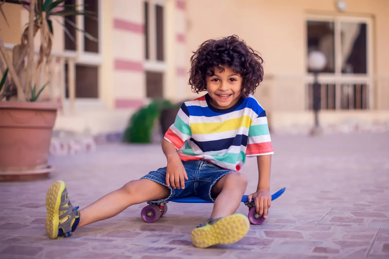Un niño pequeño está sentado en una patineta y sonriendo.