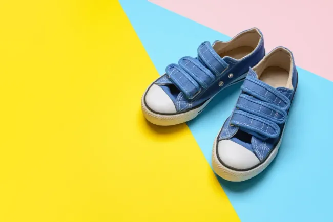 Un par de zapatillas azules sobre un fondo amarillo y rosa.