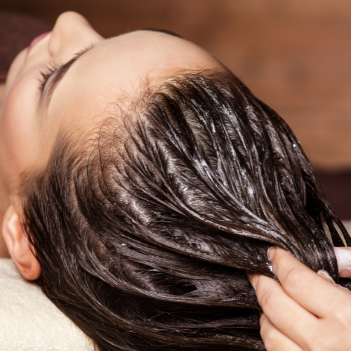 Una mujer se está tiñendo el pelo en la peluquería.