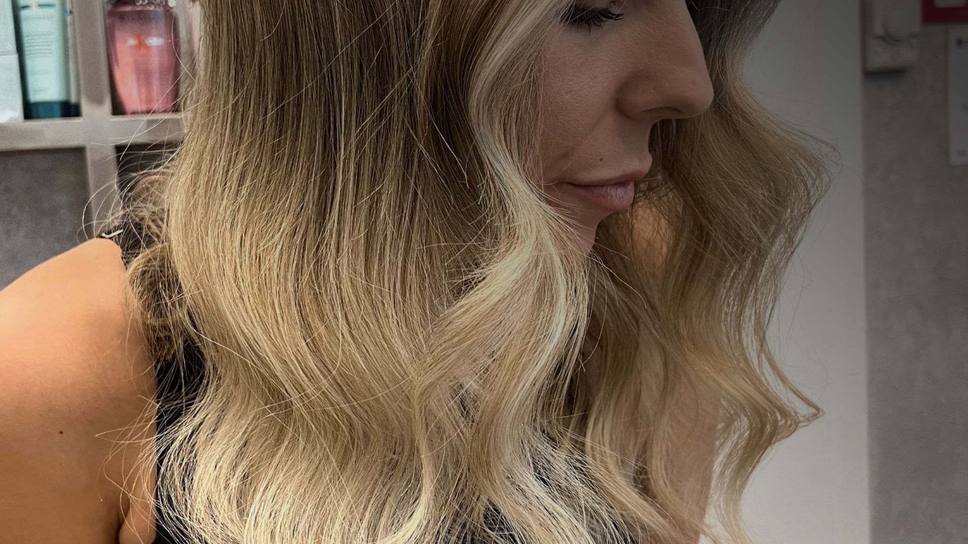 Una mujer se está cortando el pelo en una peluquera con cabello rosa.