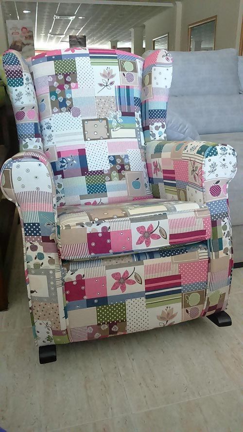 Un sillón de retazos en una tienda, con una colorida mezcla de estampados cuadrados de tela en tonos rosas, azules y neutros.