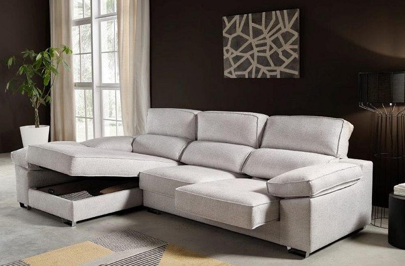 Un sofá modular gris claro con un compartimento de almacenamiento abierto, colocado contra una pared oscura con arte abstracto.