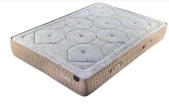 Un colchón rectangular con una superficie superior texturizada de color gris claro con un patrón de capitoné circular y laterales de color tostado.