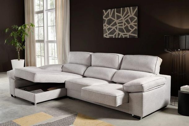 Un sofá seccional moderno de color gris claro con un compartimento de almacenamiento tipo chaise longue abierto, ubicado en una sala de estar contemporánea.