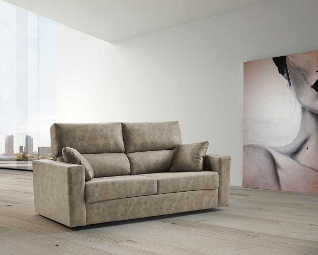 Un sofá moderno de tela color beige descansa sobre un suelo de madera clara en una habitación minimalista de paredes blancas con grandes obras de arte abstracto.